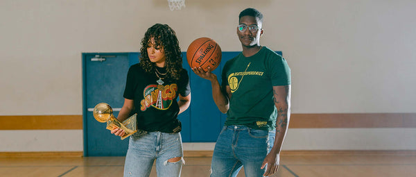 Depicts Two Models Wearing Sonics T-shirts While Holding A Trophy and Basketball.